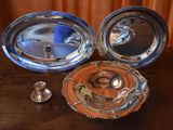 two silver dishes and a silver spoon on a wooden table
