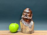 a statue of a man with a beard next to a green apple
