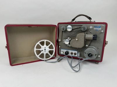 un vieux projecteur de cinéma rangé dans un coffret rouge