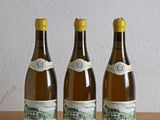 trois bouteilles de vin posées sur une table en bois à côté d'une bouteille de vin