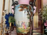 a vase with a painting on it sitting on a table