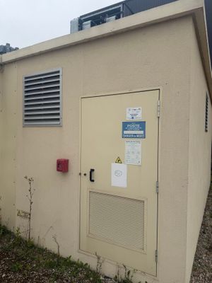 un petit bâtiment avec une porte et un climatiseur sur le côté