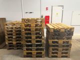 several pallets of wood stacked up in a warehouse with a red fire hydrant in the background