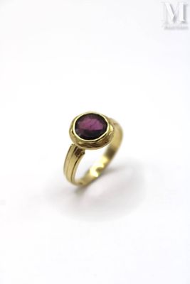 a close up of a gold ring with a purple stone