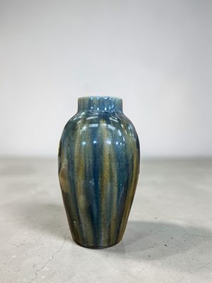 un vase bleu et vert posé par terre