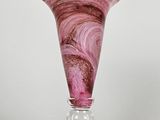 vase en verre violet orné d'un motif en spirale sur un socle transparent