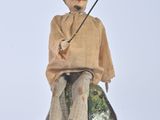 a figurine of a man sitting on a rock with a fishing pole