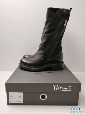 un gros plan sur une paire de bottes noires posées sur une boîte