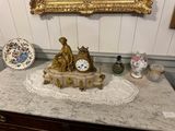a gold clock on a marble table with a mirror above it