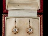 une image représentant une paire de boucles d'oreilles dans un écrin, sur fond noir