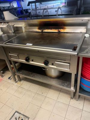 une grande cuisinière dans une cuisine, sur laquelle sont posés de nombreux plats