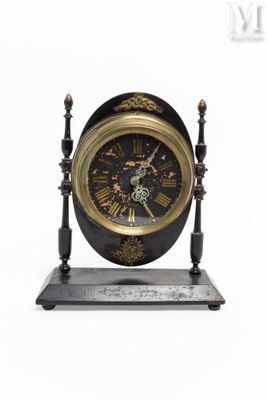 une horloge noire et dorée posée sur un socle, sur fond blanc
