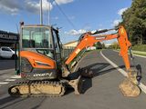 an orange excavator that is parked on the side of the road