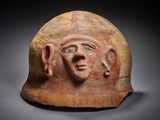 a close up of a clay helmet with a face on it