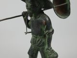 bronze figurine of a boy with a trumpet and a hat