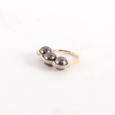 an image of a close up of two black pearls on a gold ring