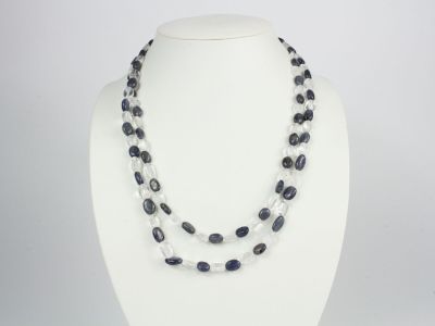un gros plan d'un collier porté par un mannequin, composé de perles noires et blanches