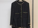 black jacket hanging on a hanger in front of a beige wall