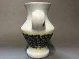 a white vase with a black and yellow design on it
