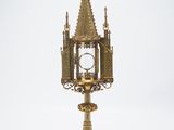 une horloge ancienne en laiton posée sur un socle, avec un cadran au centre