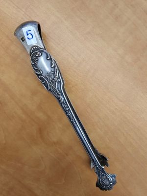 une cuillère en argent avec un manche en argent posée sur une table en bois