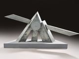 a metal sculpture of a triangle and a pair of scissors on top of it