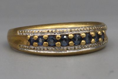 gros plan d'une bague en or avec des saphirs bleus