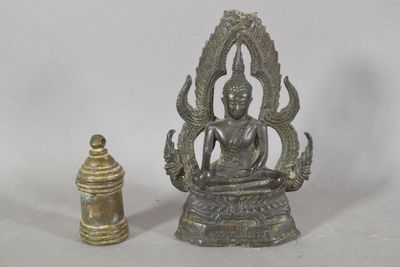 une statue de Bouddha assis en position du lotus, à côté d'une petite cloche