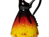 a black and yellow vase with a handle on a white surface