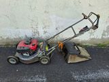 a lawn mower that is sitting on the ground next to a trash can