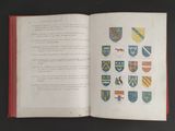 un livre ouvert sur lequel figure l'image d'un blason et un blason