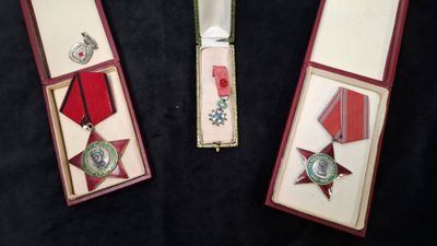 trois médailles et un couteau dans une boîte posée sur une surface noire