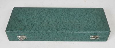 une vieille valise verte posée sur une table blanche