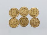 six gold sovereigns, one of which has a crown on it