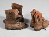 deux paires de bottes marron posées sur une surface blanche