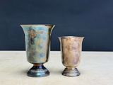 two silver vases sitting on a table next to each other