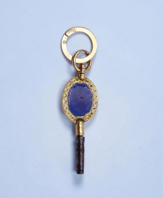 une clé en or sertie d'une pierre bleue