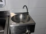 un lavabo en acier inoxydable et un sèche-mains en acier inoxydable dans des toilettes publiques