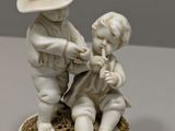 a figurine of a boy and a girl playing with a dog