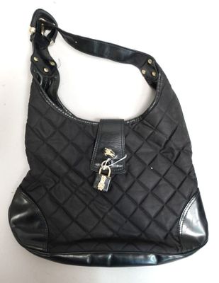 un gros plan d'un sac à main noir posé sur une surface blanche