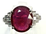 a close up of a ring with a red stone surrounded by diamonds