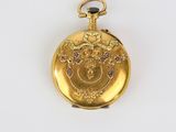 a close up of a gold pocket watch on a white surface
