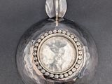 an image of a silver pendant with a coin in the center