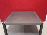 table basse grise posée sur un sol recouvert de moquette, devant un mur rouge