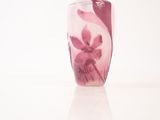 a vase with a pink flower on it on a white surface