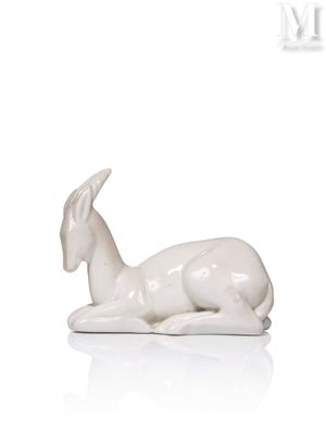 a statue of a goat laying down on a white surface