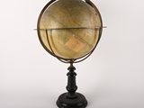 an old globe on a black stand against a white background