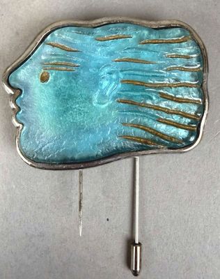 a blue fish shaped brooch on a silver pin