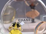 a small figurine of a woman in a yellow dress next to a bottle of chanel perfume
