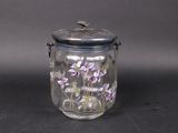 a glass jar with purple flowers in it on a table